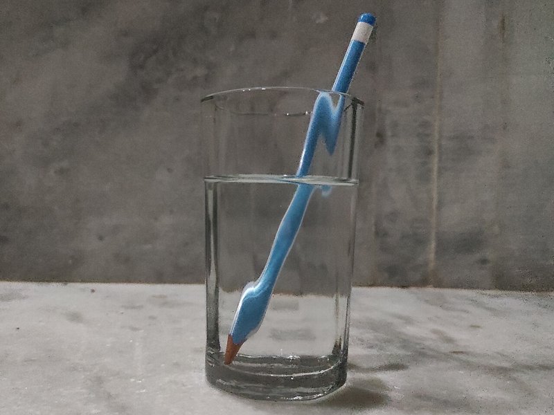 A pencil in a glass of water appears bent at the surface of the water